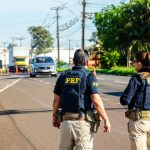 Agentes da PRF monitoram o trânsito em uma rodovia brasileira durante o dia.