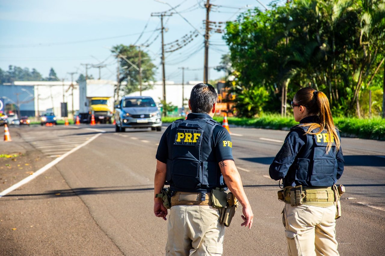 Agentes da PRF monitoram o trânsito em uma rodovia brasileira durante o dia.