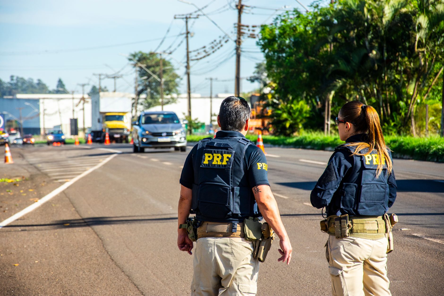 Agentes da Polícia Rodoviária Federal monitoram o tráfego em uma rodovia brasileira durante o dia.